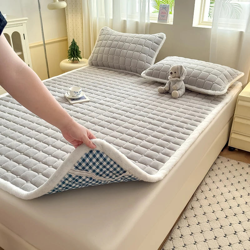 Gray fleece sheet lifted to reveal checked backing and an elastic corner strap.