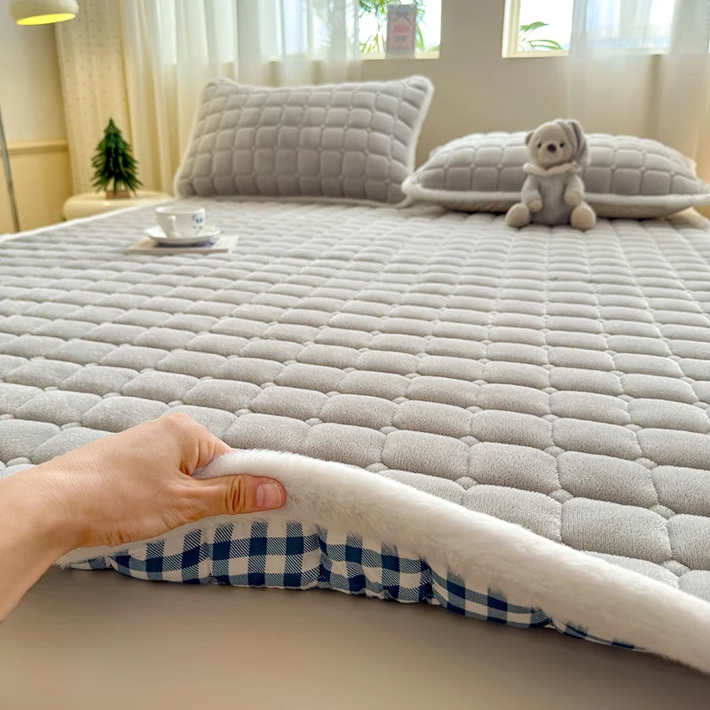 Hand lifting the white-edged corner of gray fleece bedding to show checked backing.
