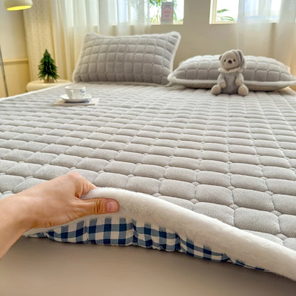 Hand lifting the white-edged corner of gray fleece bedding to show checked backing.